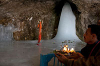 عبادت زائر هندي در جلوي يخ، در غاري در كشمير. هر ساله صدها هزار هندو براي زيارت  به غار دوري در هيمالايا ميروند تا ساختار يخي كه معتقدند نشان خداي شيوا است را ببينند.