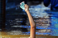 
	یک نوجوان تایلندی درحالی که در آب سیل شنا می&zwnj;کند پول&zwnj;های خود را بالا نگه داشته تا خیس نشود.
